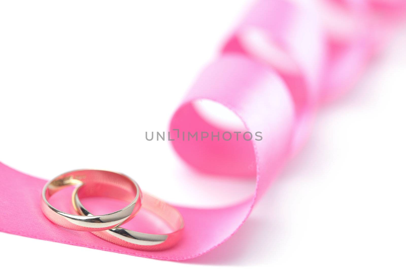 Gold wedding rings over pink ribbon isolated
