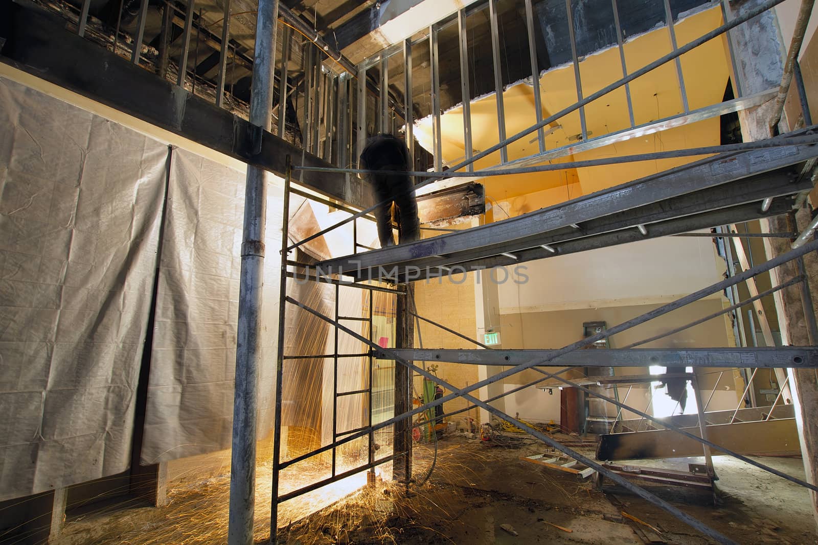 Construction Worker with Blow Torch Welding and Cutting Steel Support on Scaffolding