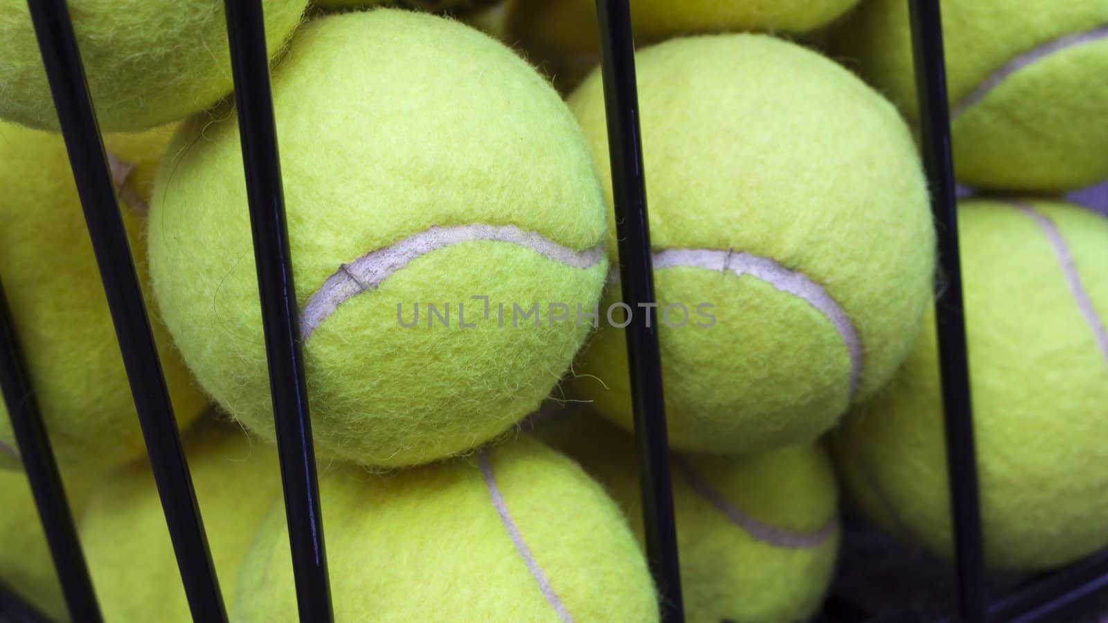 Some tennis balls stored in steel baskets