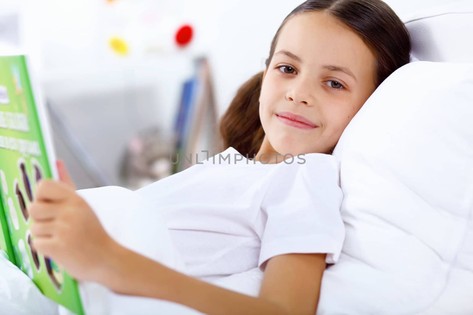 Portrait of girl with a book in bed at home