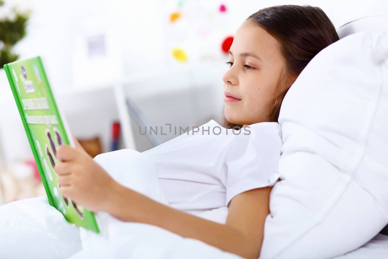 Portrait of girl with a book in bed at home