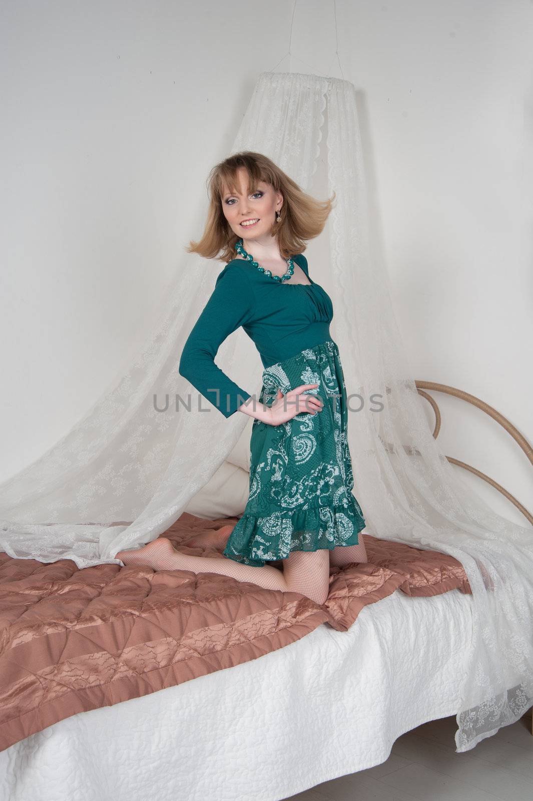 Sexy woman in green dress on the bed