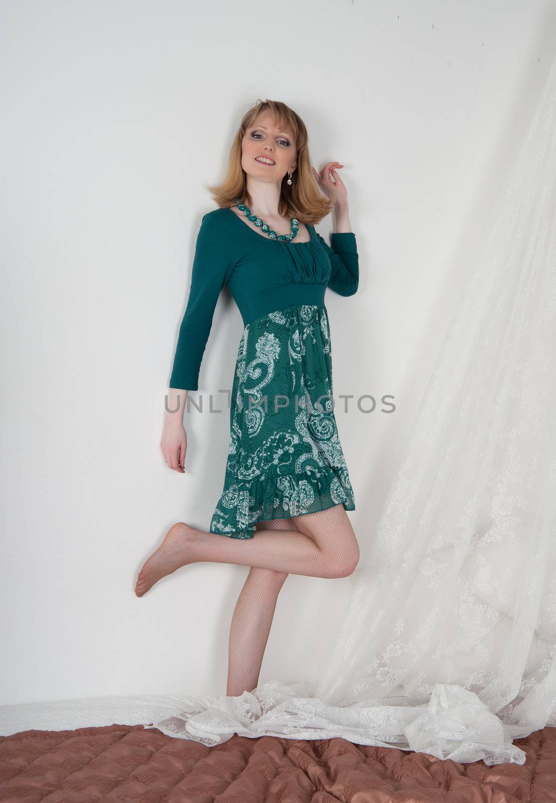 Sexy woman in green dress on the bed