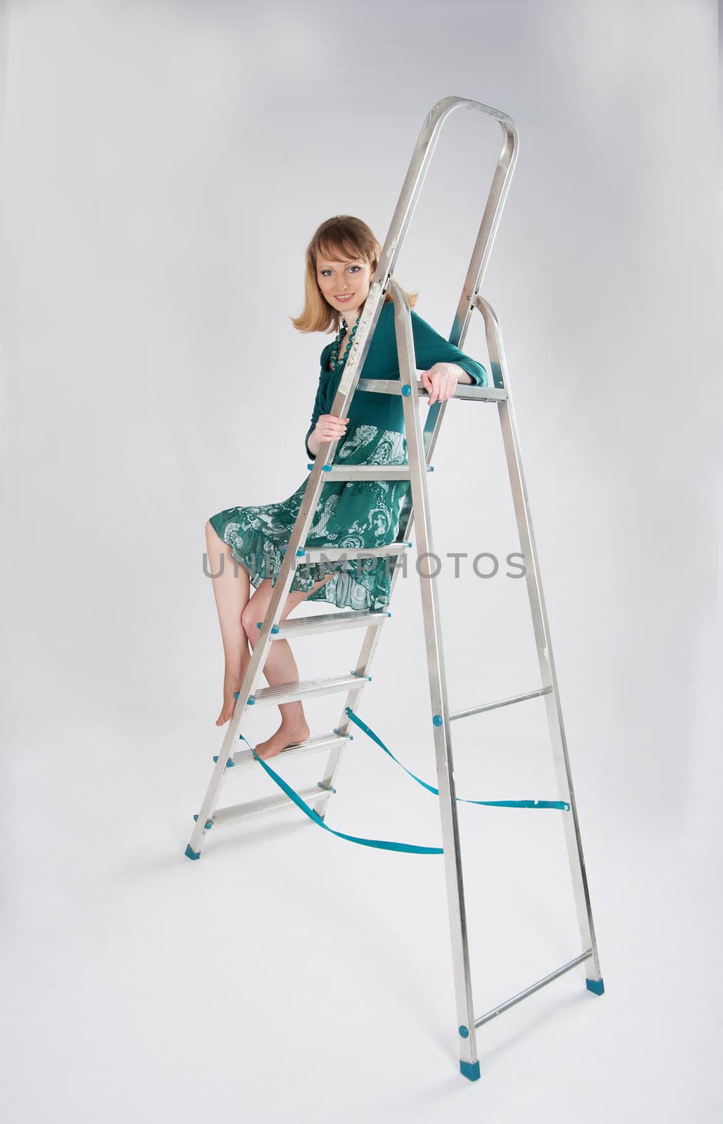 beautiful woman in a green dress sitting on a stepladder