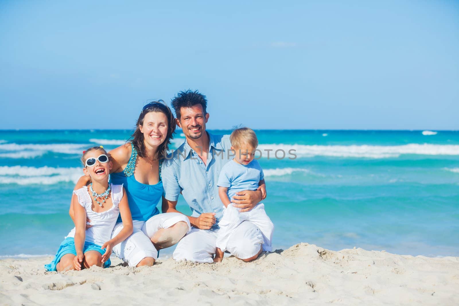 Family of four having fun on tropical beach