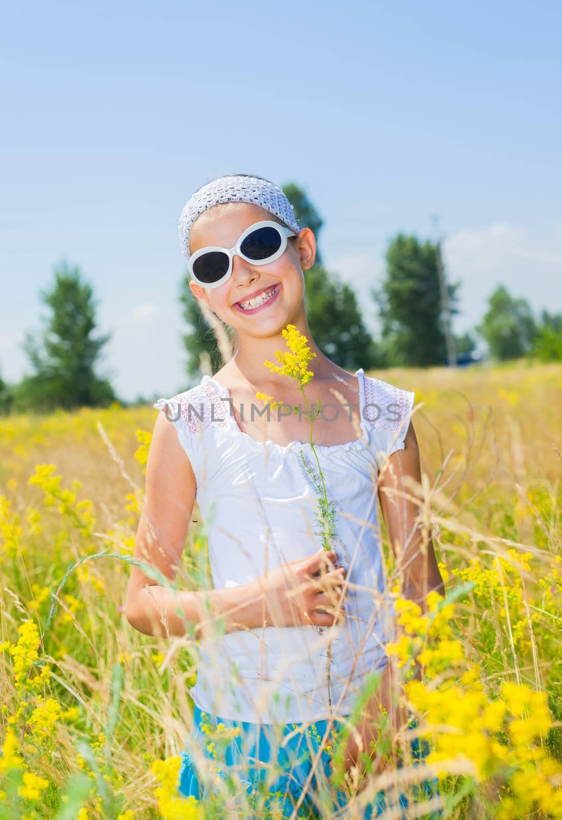 Adorable girl in glasses with flowers in yellow field. Summer freedom andjoy concept. Vertical view