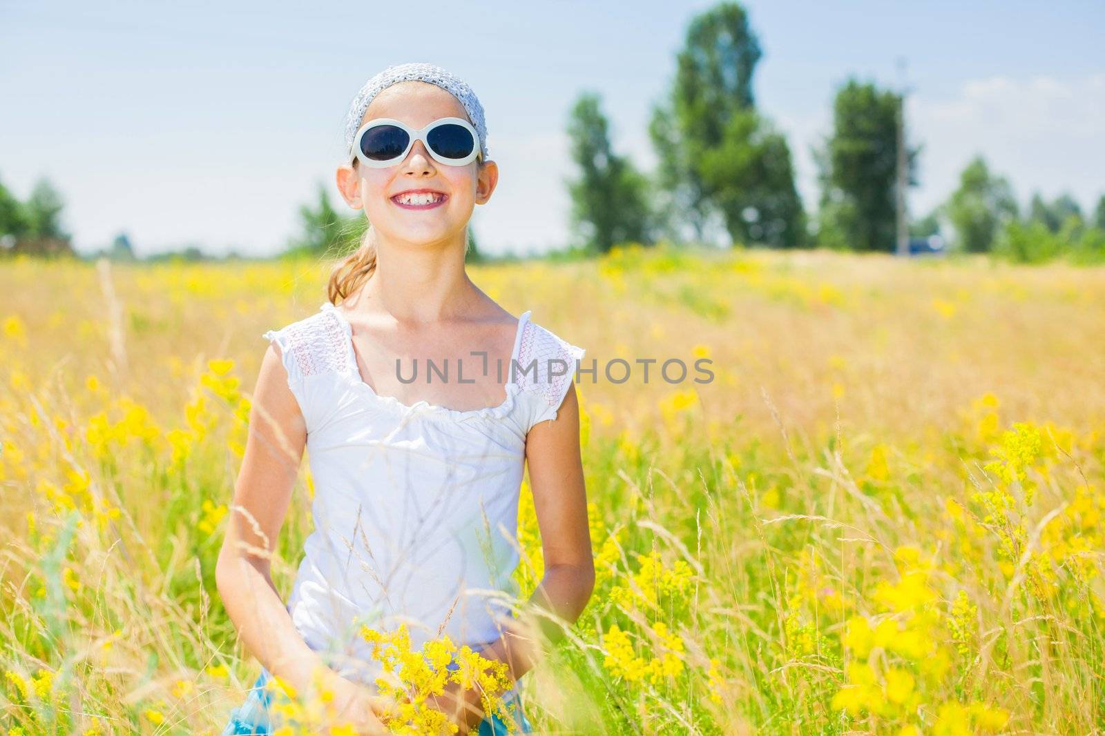 Adorable girl in glasses with flowers in yellow field. Summer freedom andjoy concept.