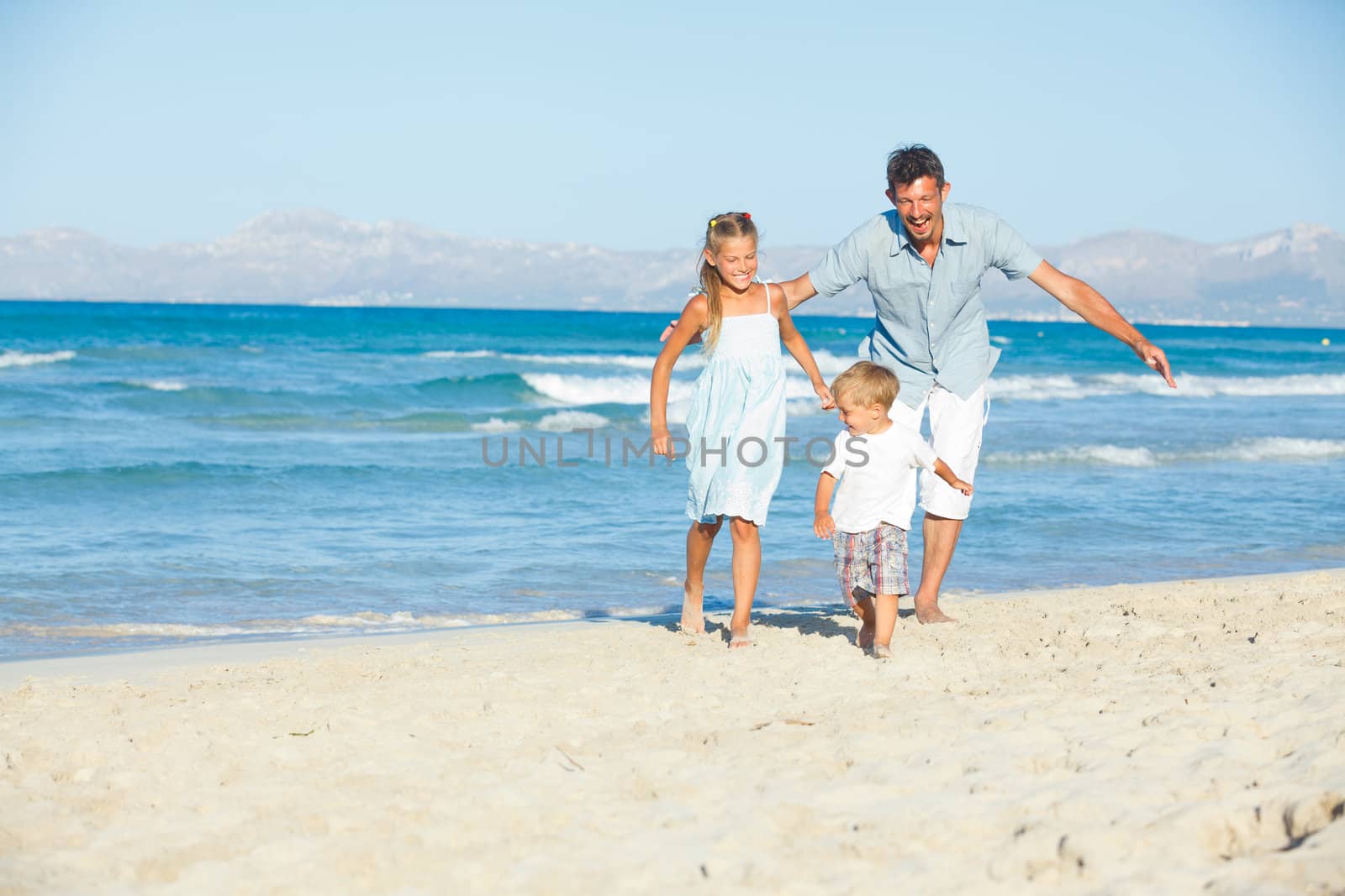 Happy family of three sitting and having fun on tropical beach