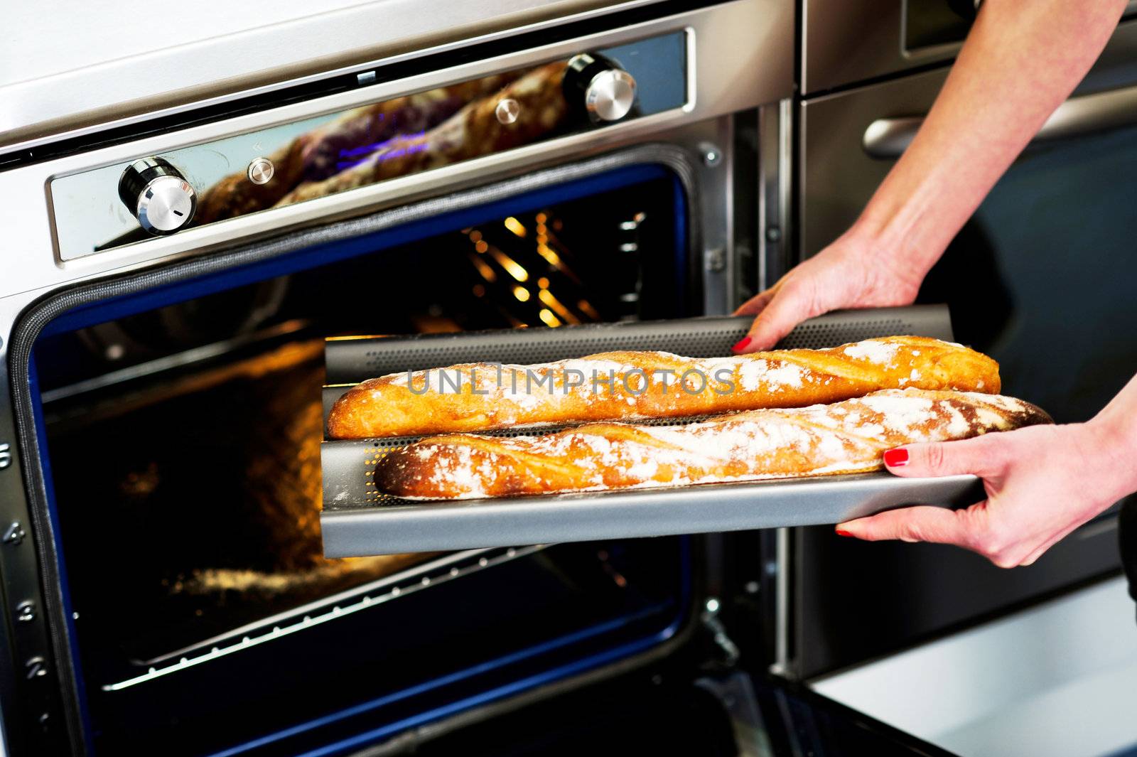 Hands of a woman holding hot baguette. Ready to be served