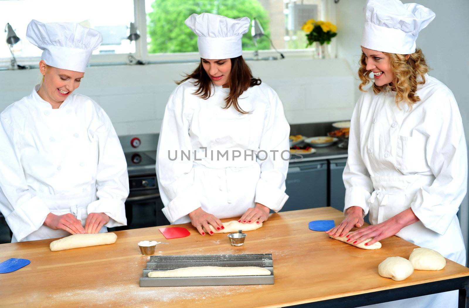 Beautiful female chefs kneading dough. Watching and learning