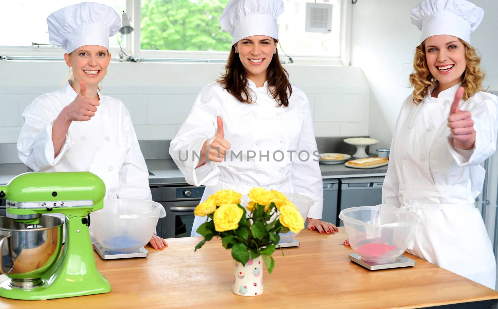 Professional female chefs showing thumbs up by stockyimages