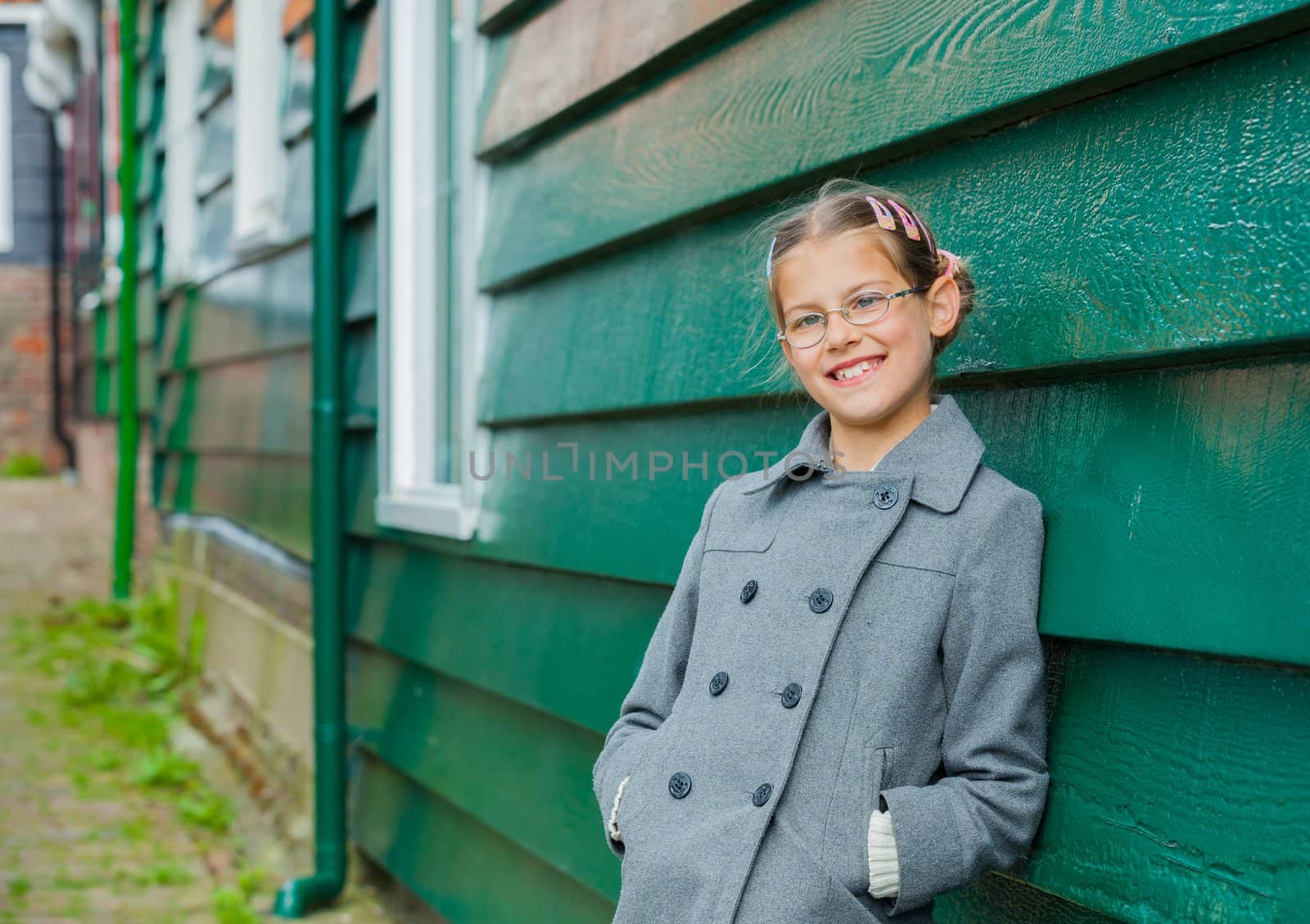 Young girl near green wooden wall looking at the camera
