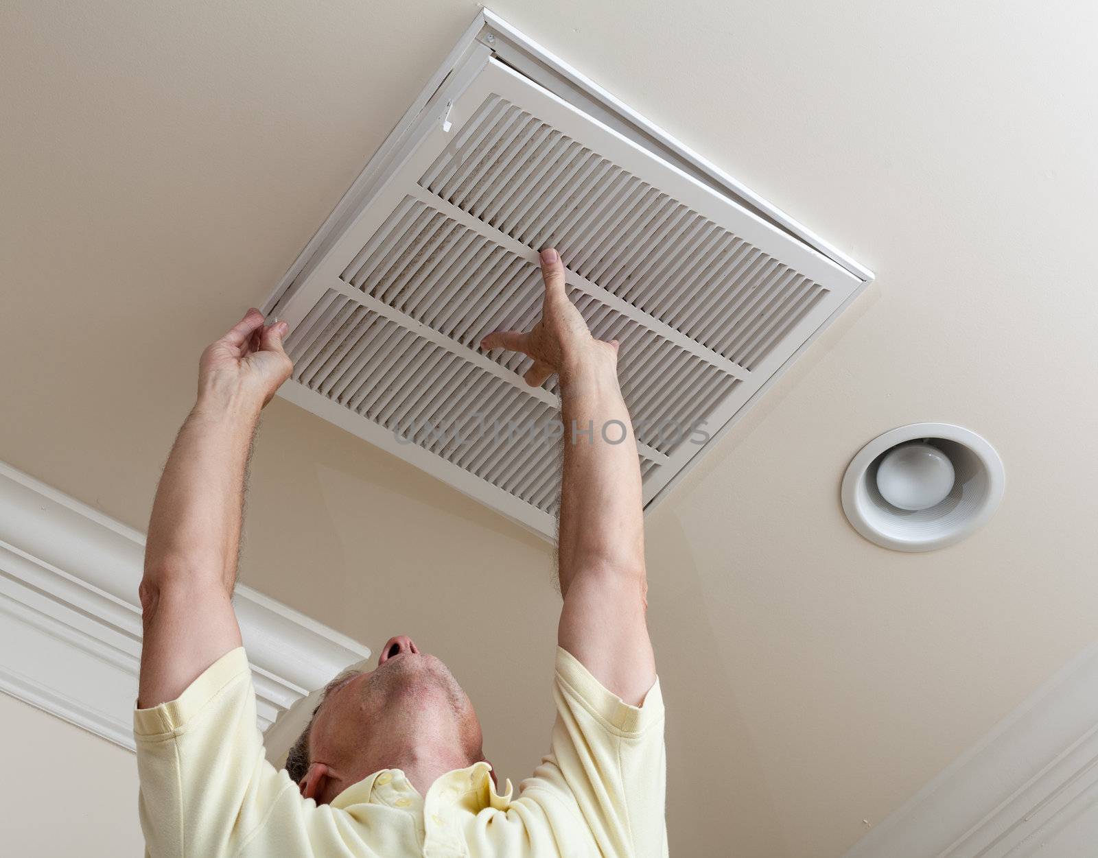 Senior man opening air conditioning filter in ceiling by steheap