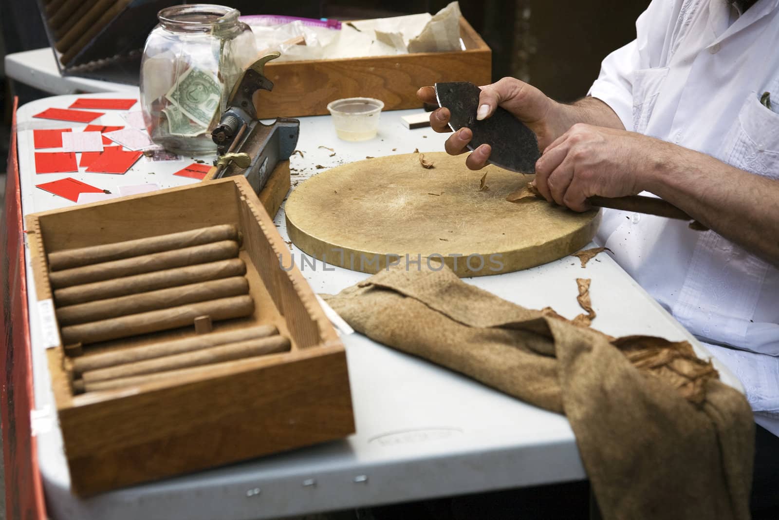 Man hand-rolling cigars at a table.







Rolling cigars
