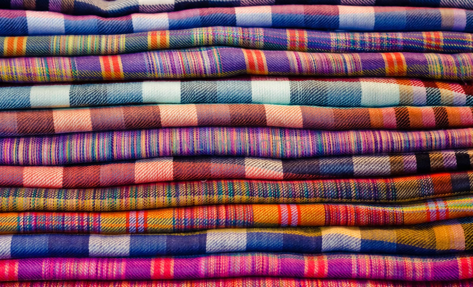 Stack of colorful fabrics at market  by ryhor