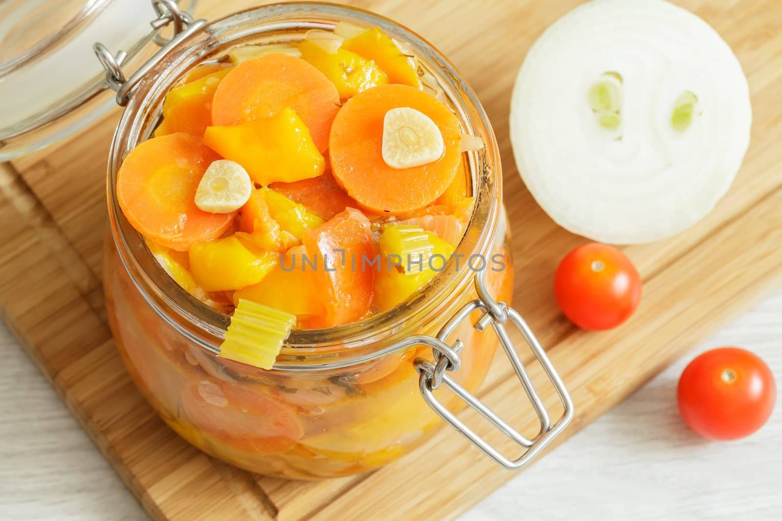 Glass jar with stewed vegetables, onion and cherry tomatoes on the cutting board