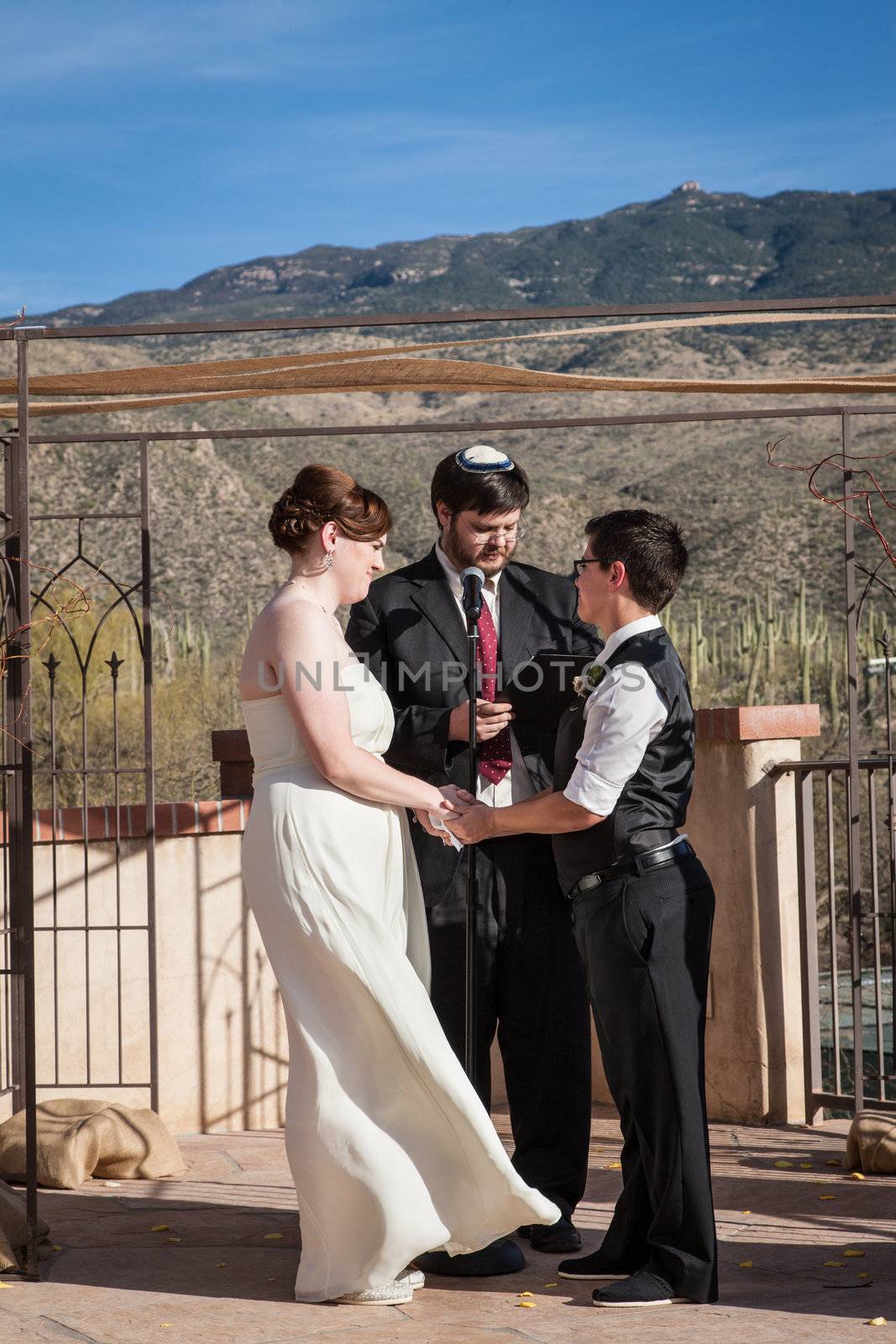 Rabbi reading sacrament for happy lesbian couple marring outdoors