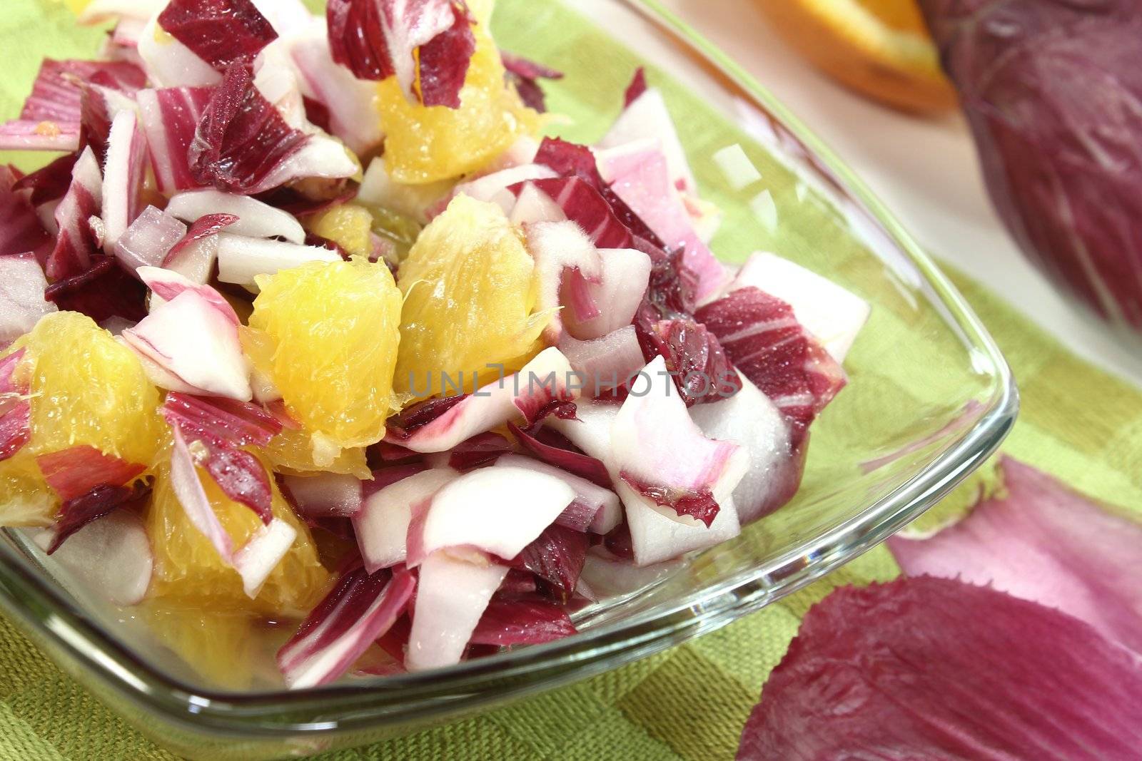 fresh red chicory salad with fresh orange slices and dressing on a green napkin