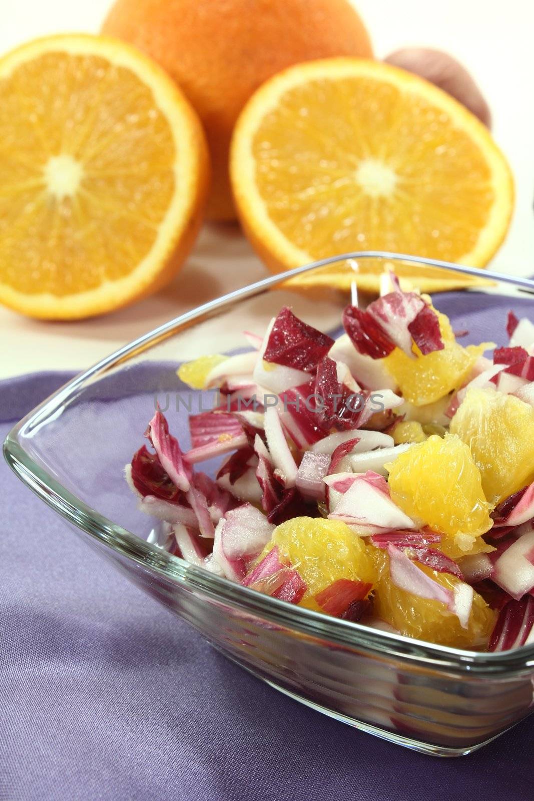red chicory salad with fresh orange slices and dressing on a purple napkin