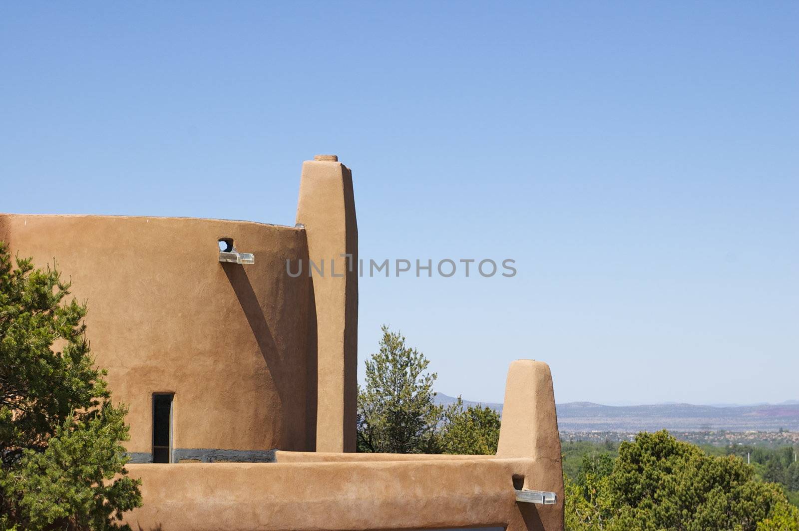 New Mexico curved Adobe Building with a backdrop looking out over Santa Fe, against a blue sky with copy space.