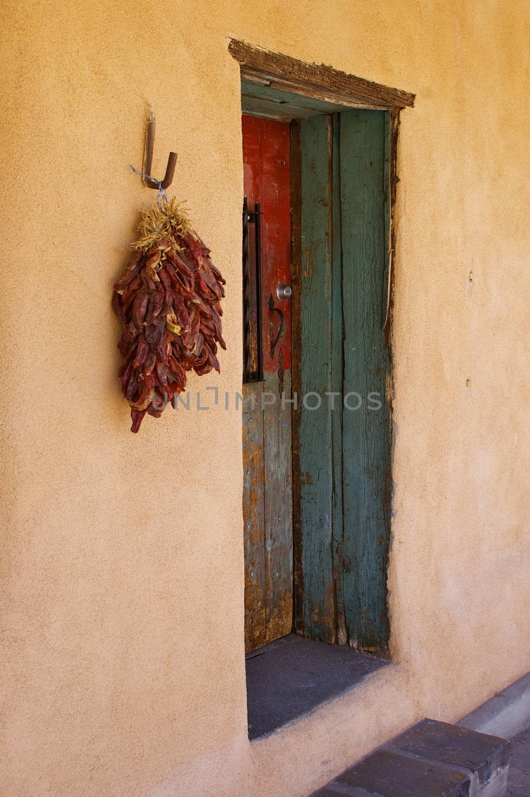 New Mexican Adobe Building, featuring a characterful doorway and chilli peppers hanging on the wall, with copy space.