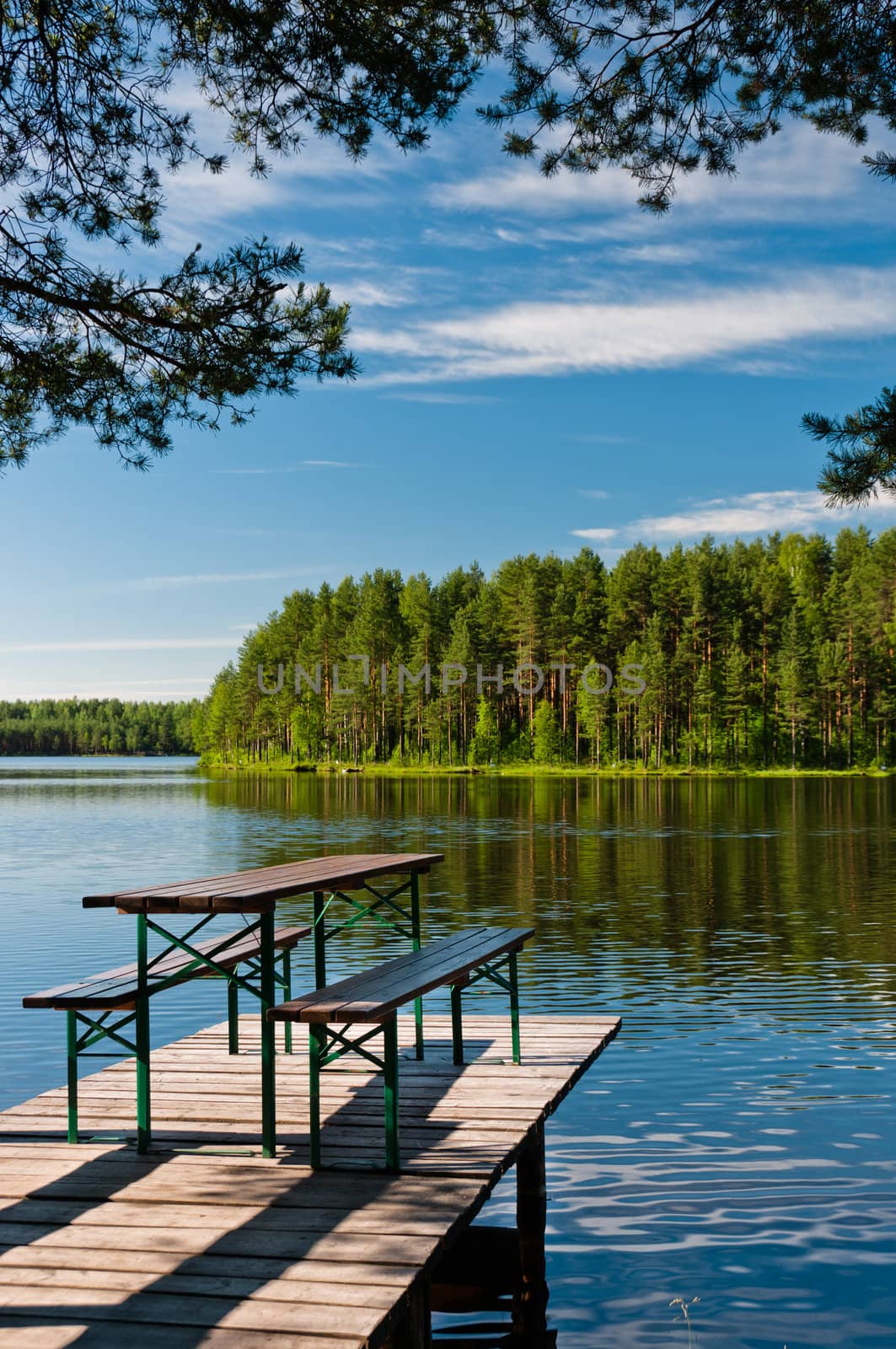 Wooden pier on lake with benches, beautiful nature view