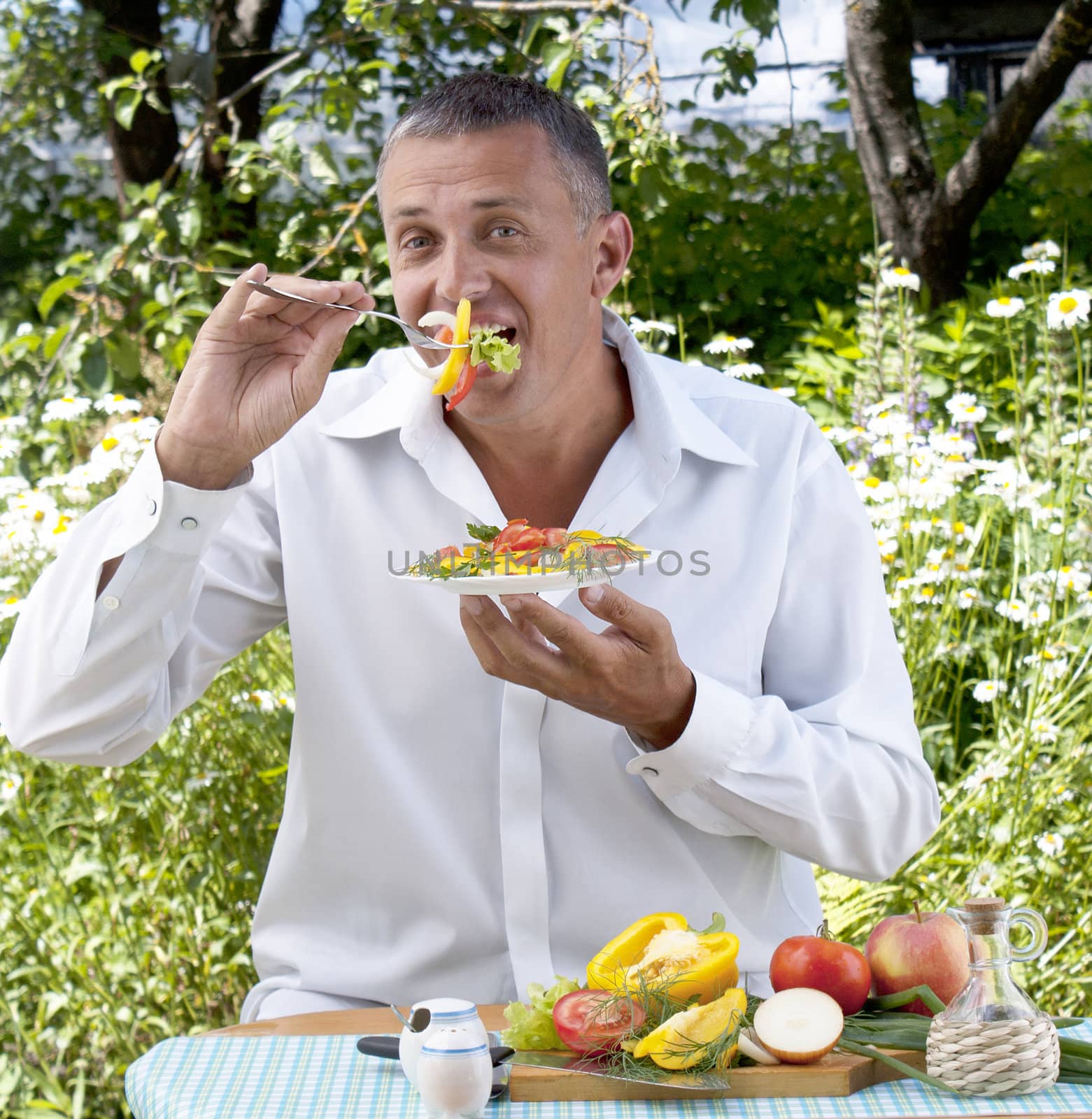 The man the vegetarian tastes salad from fresh appetizing vegetables