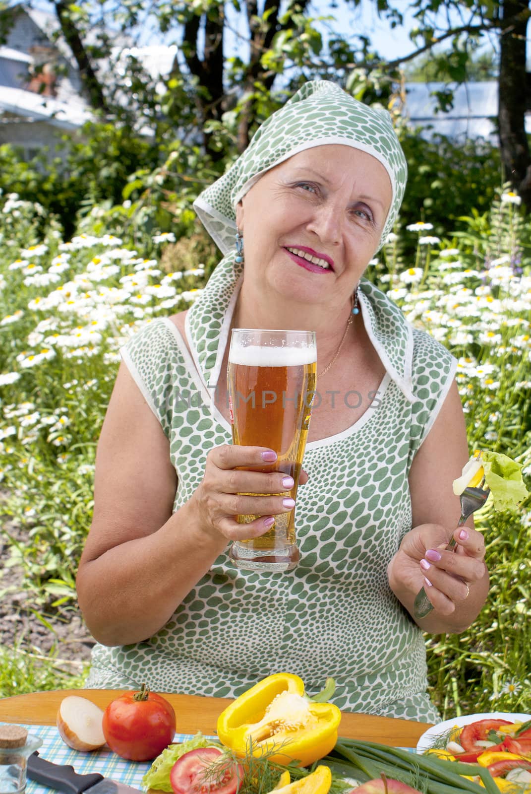 The adult woman drinks the fresh cooled dark barley beer with salad from fresh vegetables