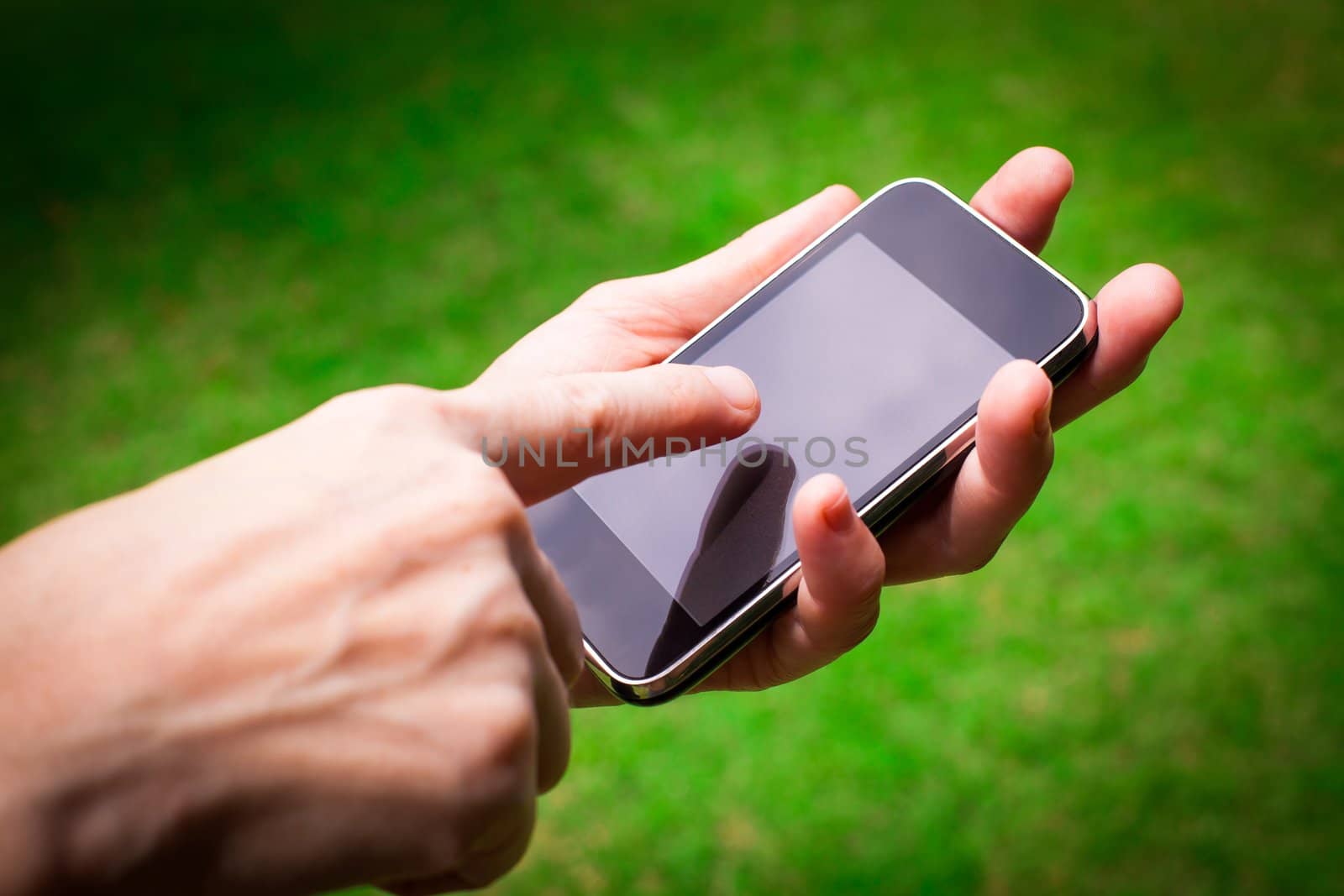 Mobile phone in the hand    on background of green grass