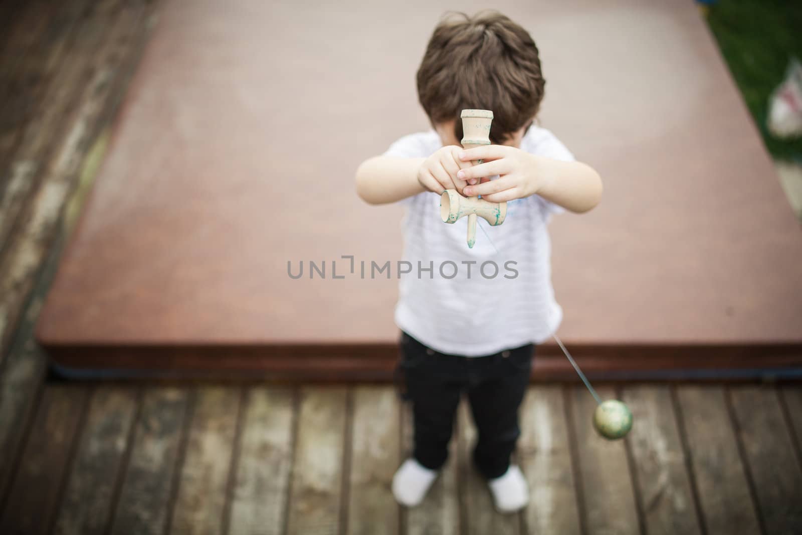 Boy playing cup and ball by Talanis