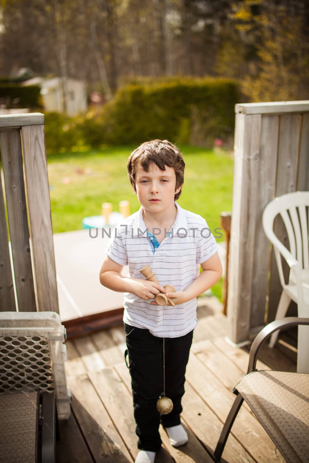 Boy playing cup and ball outside on a patio