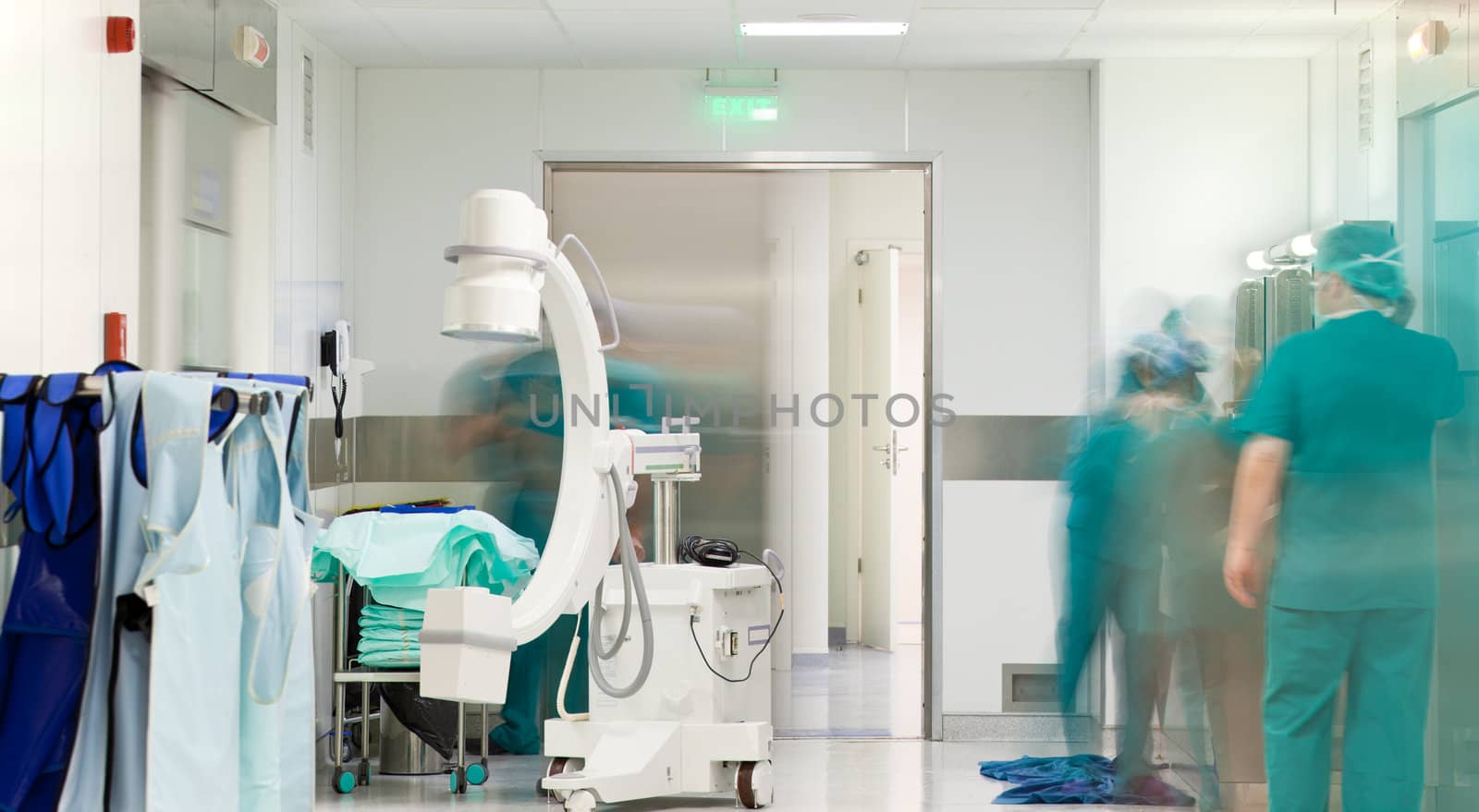 Mobile X-Ray machine in hospital corridor in front of surgery, blurred doctor figures