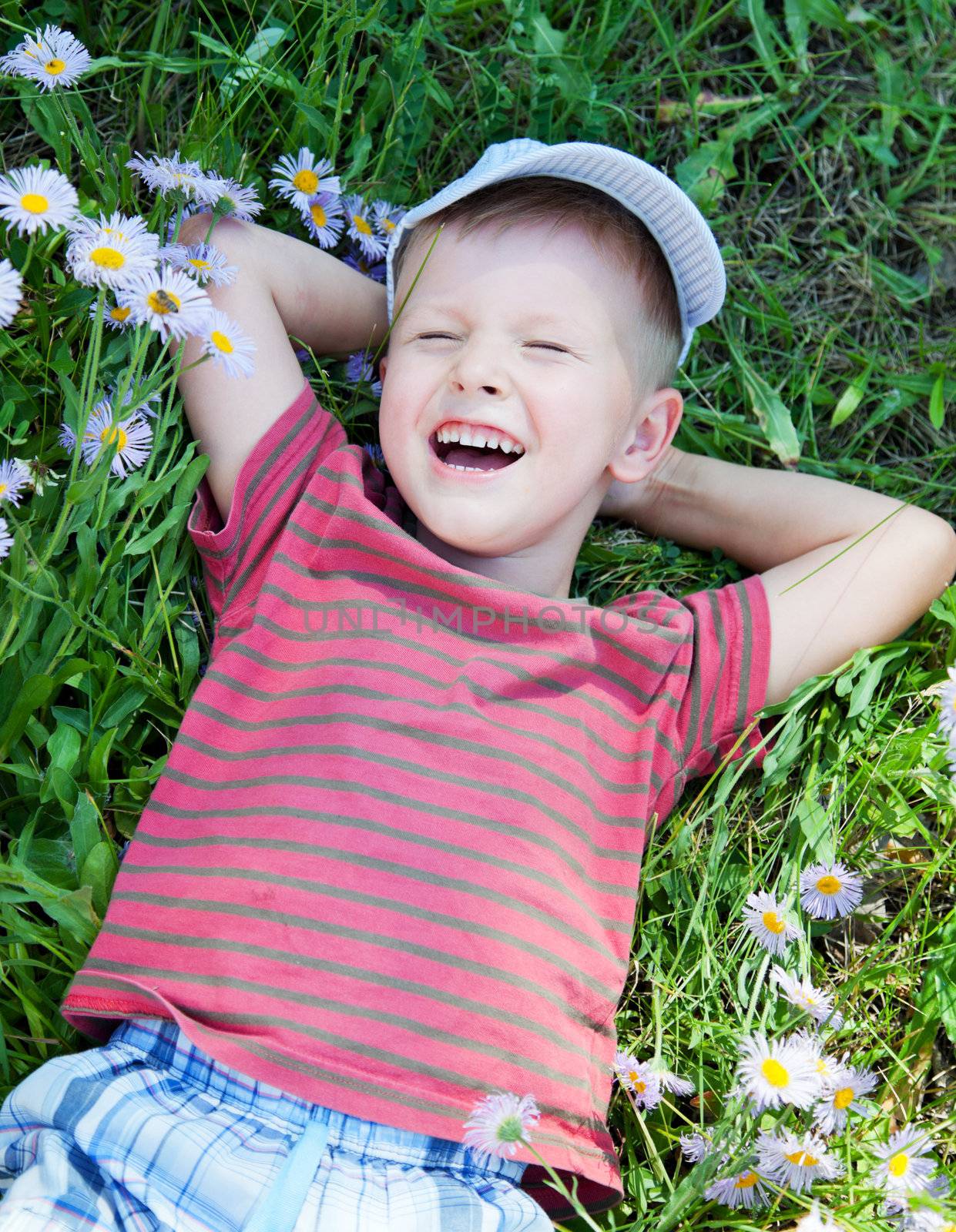 Small boy lying on the grass and laughing