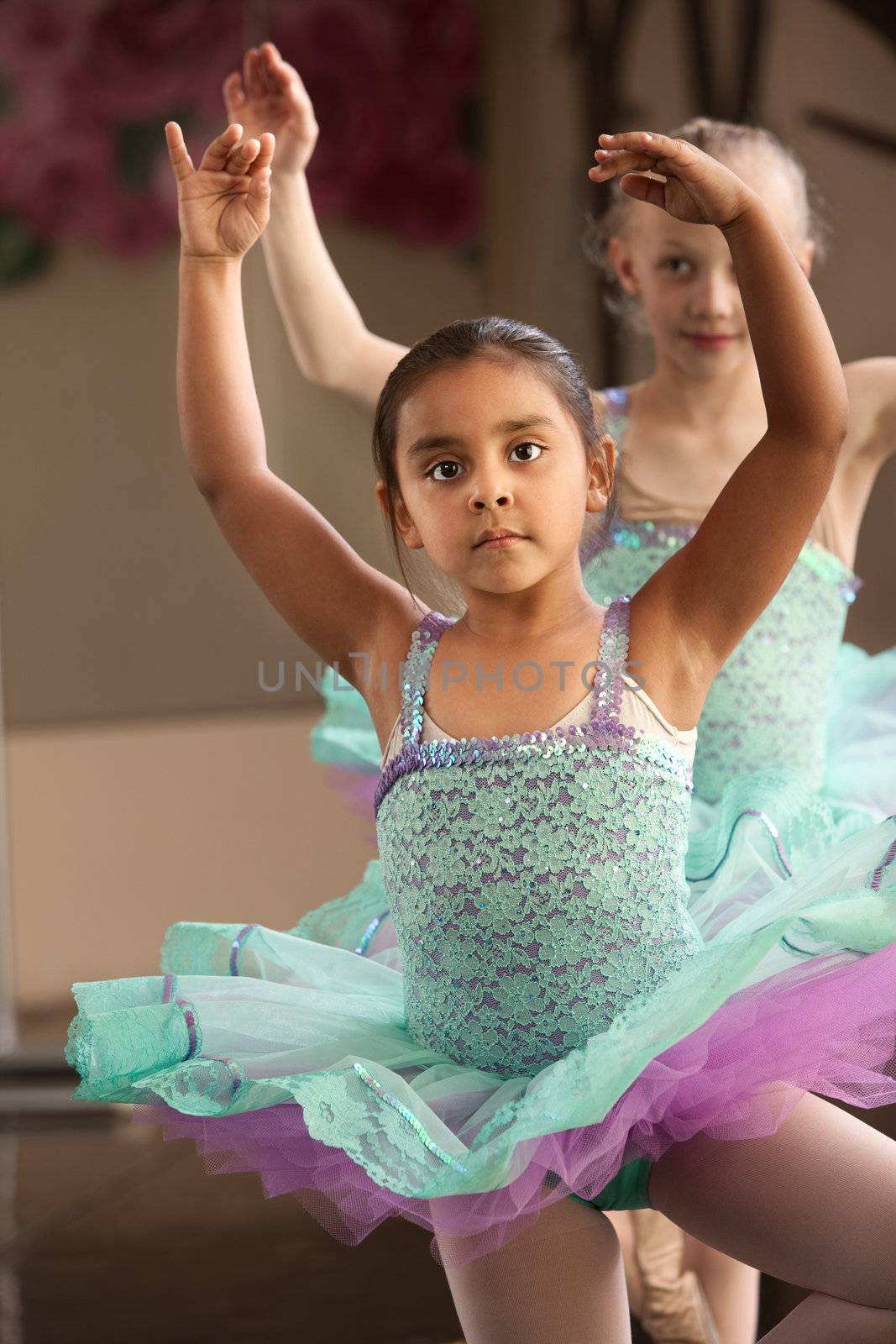 Cute little girls in ballet dresses practice in a studio