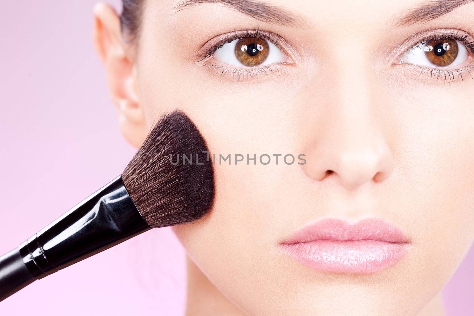 girl doing makeup with powder brush