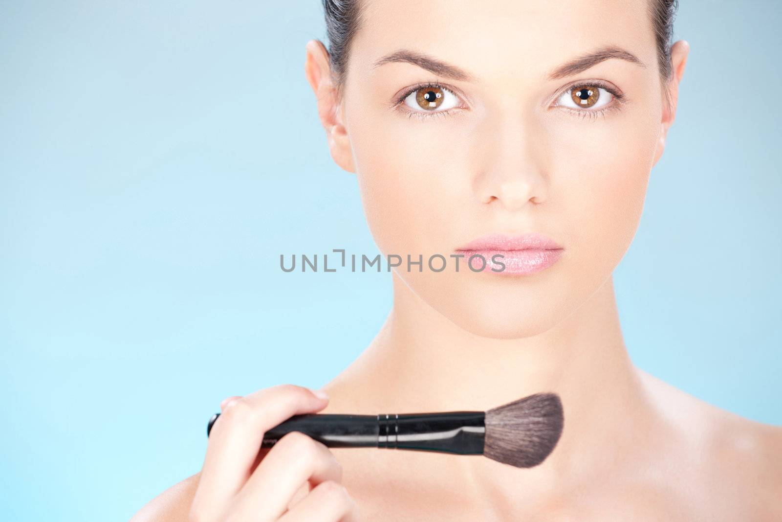 Portrait of a pretty young woman holding powder brush