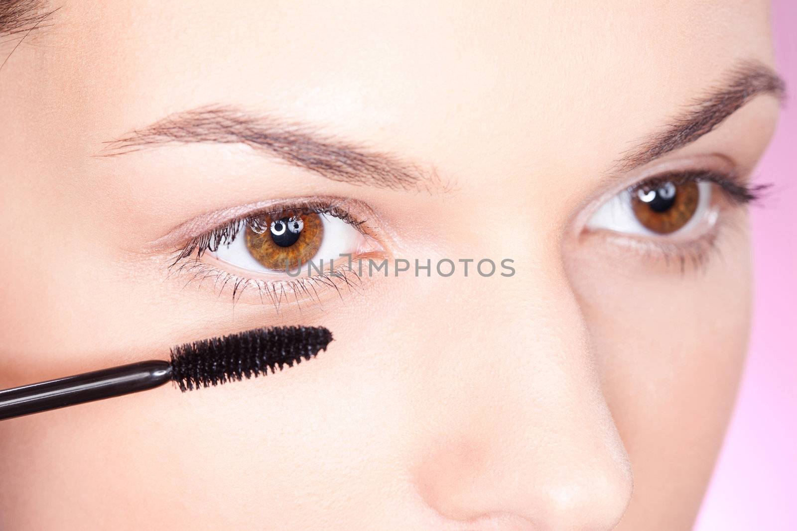 pretty woman applying mascara on eye