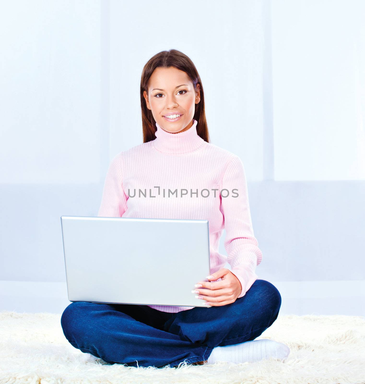 Pretty young woman with laptop on carpet at home