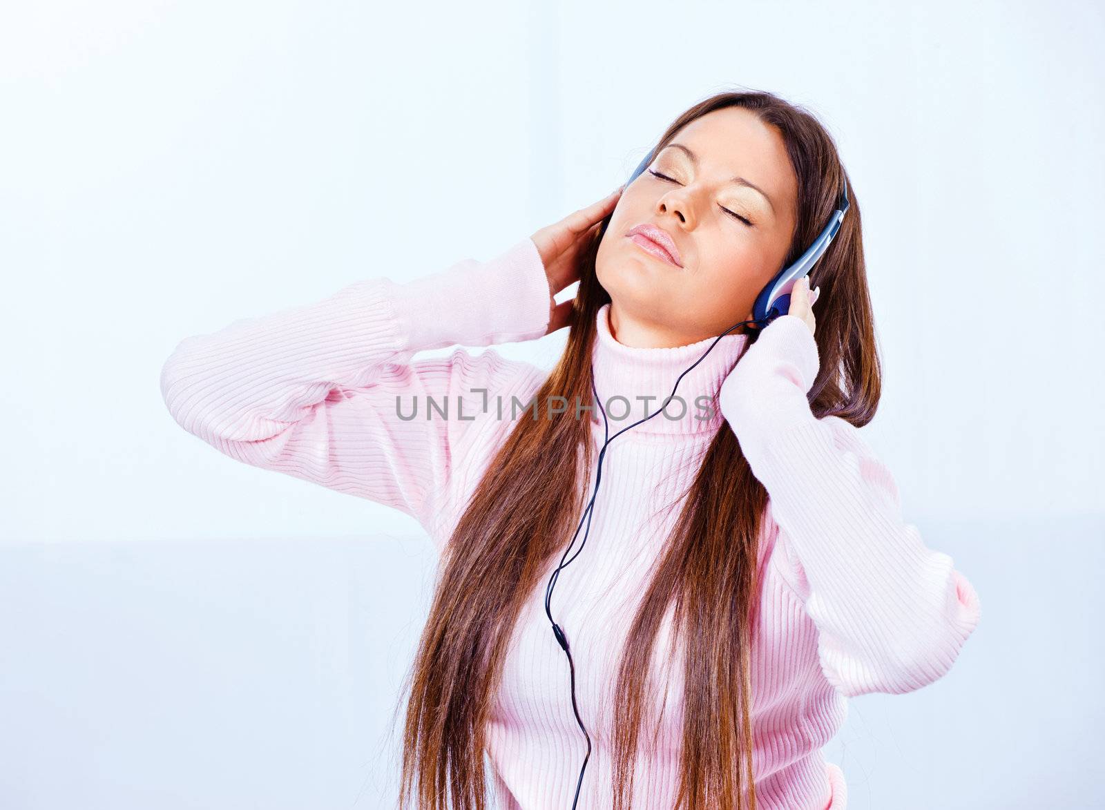 Pretty young woman with headphones listening music at home