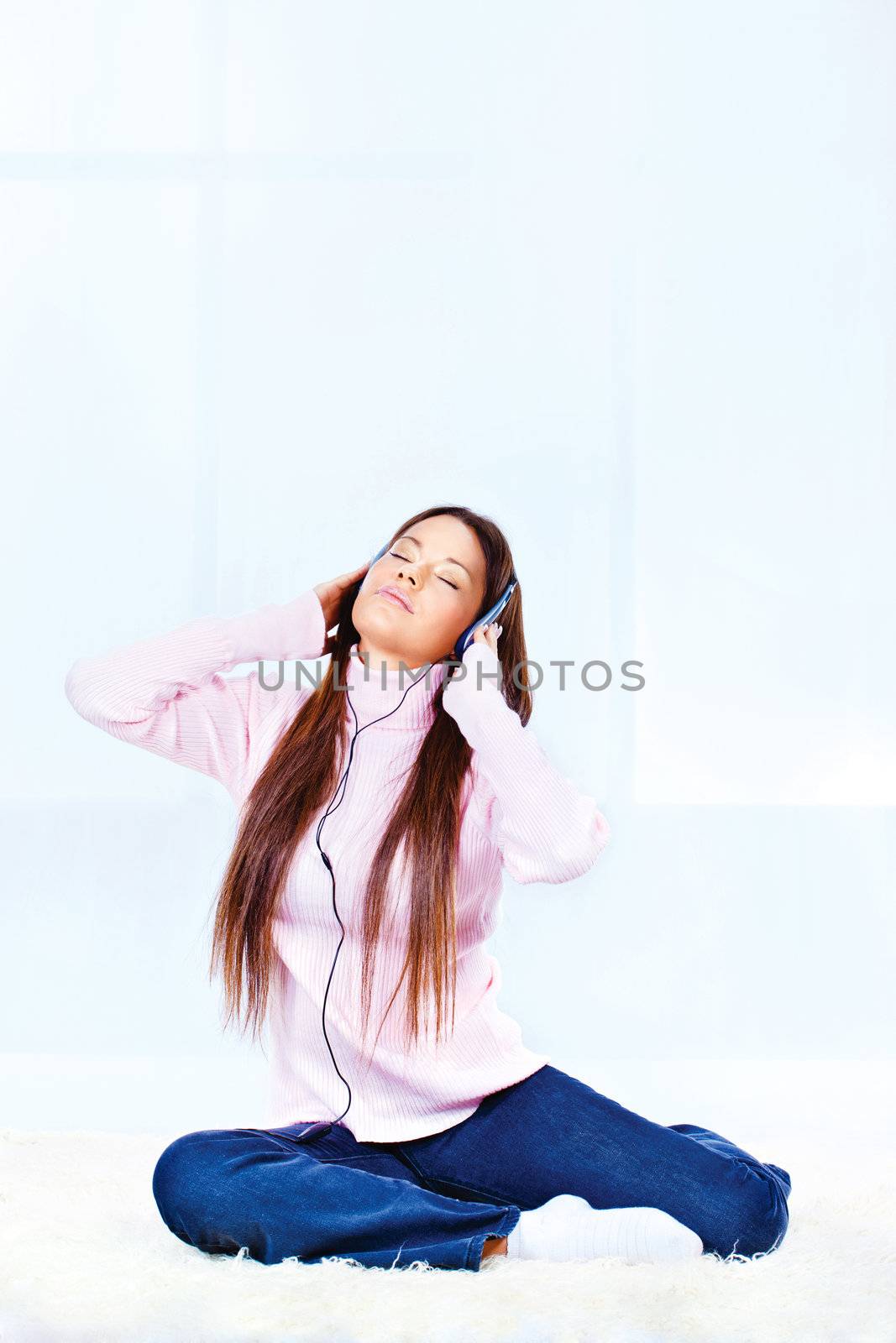 Pretty young woman with headphones listening music at home