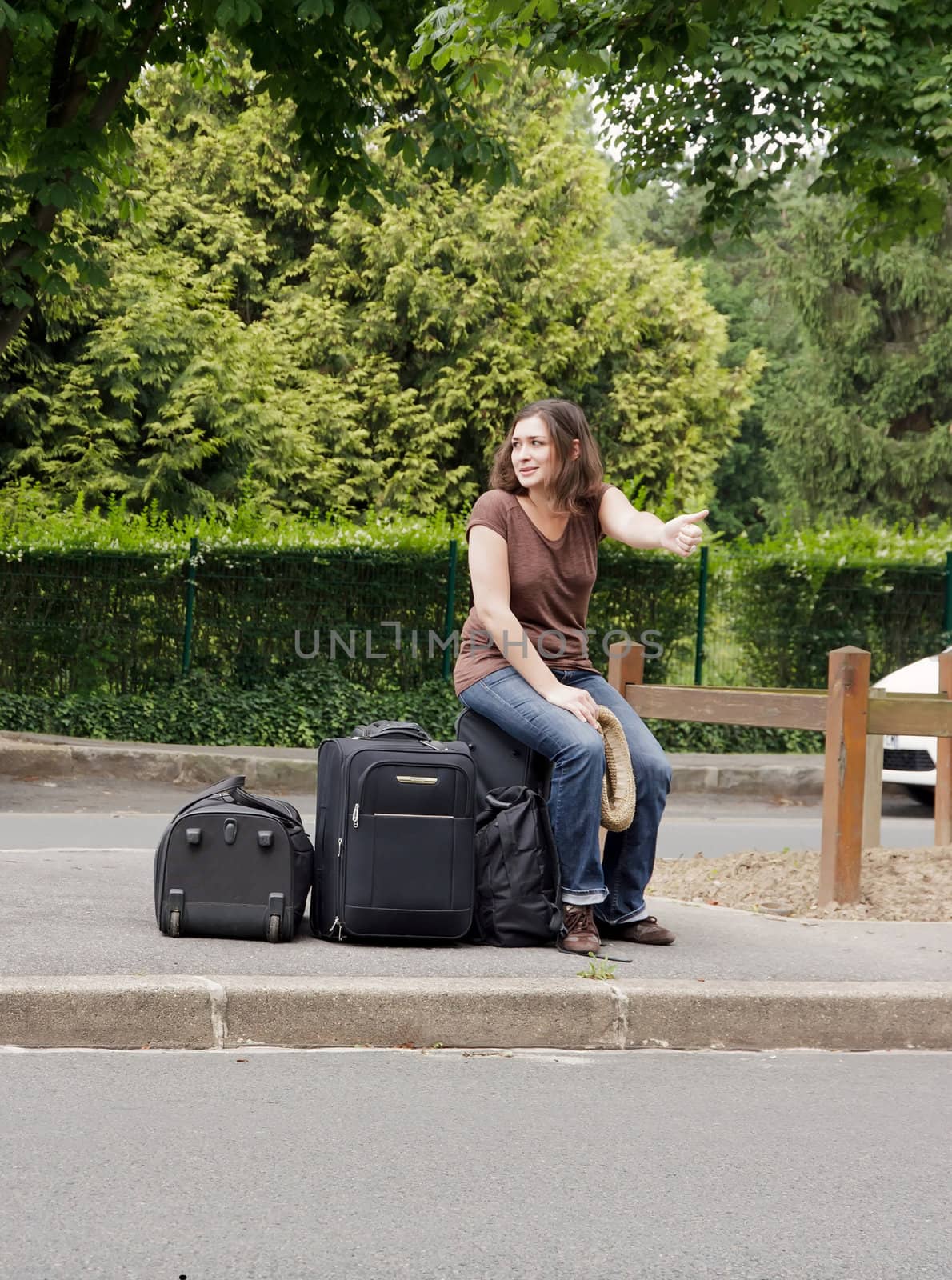 woman making hitchhiking, sitting on his luggage