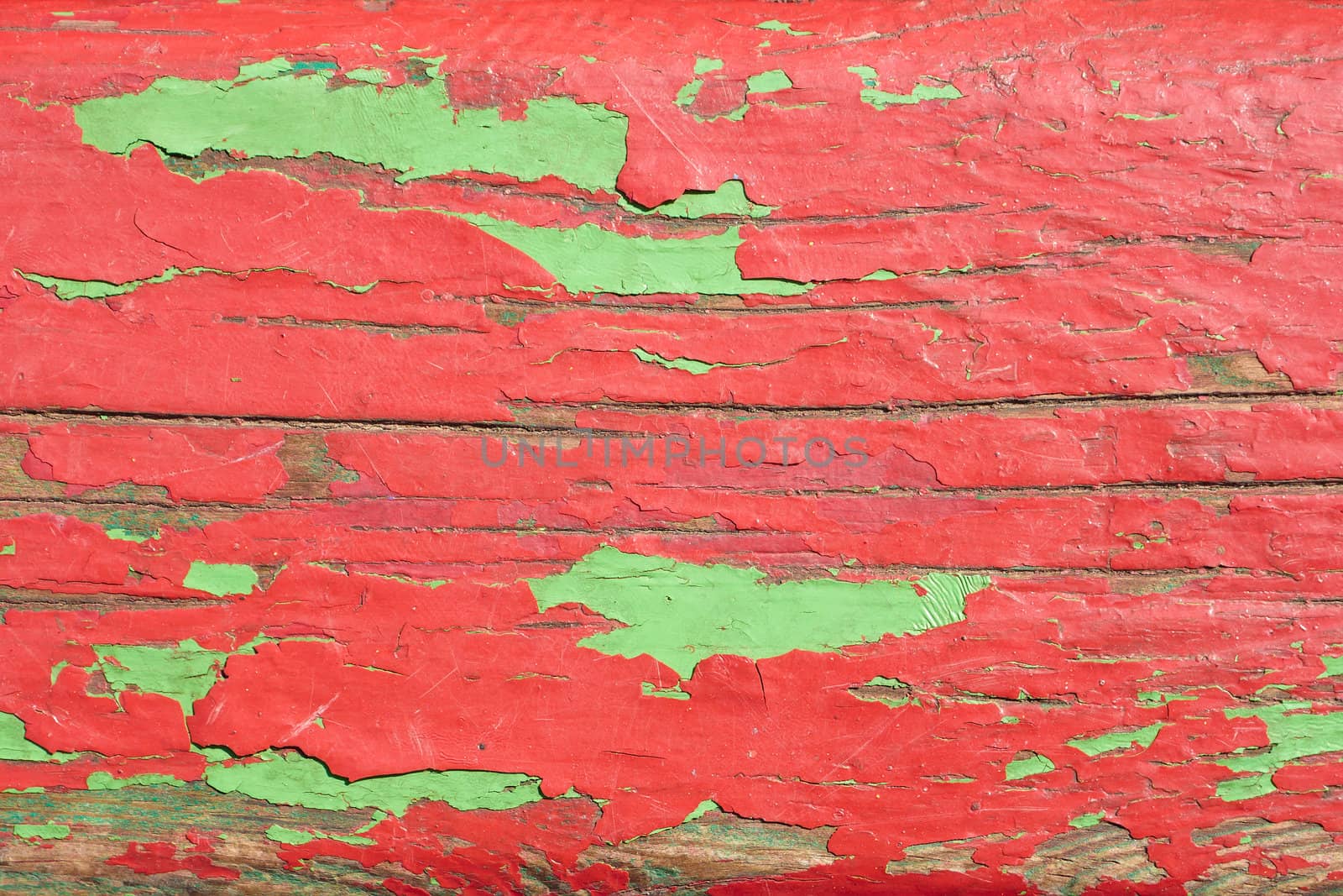 Detail of old wooden boards painted in red and green with several layers of shelled paint