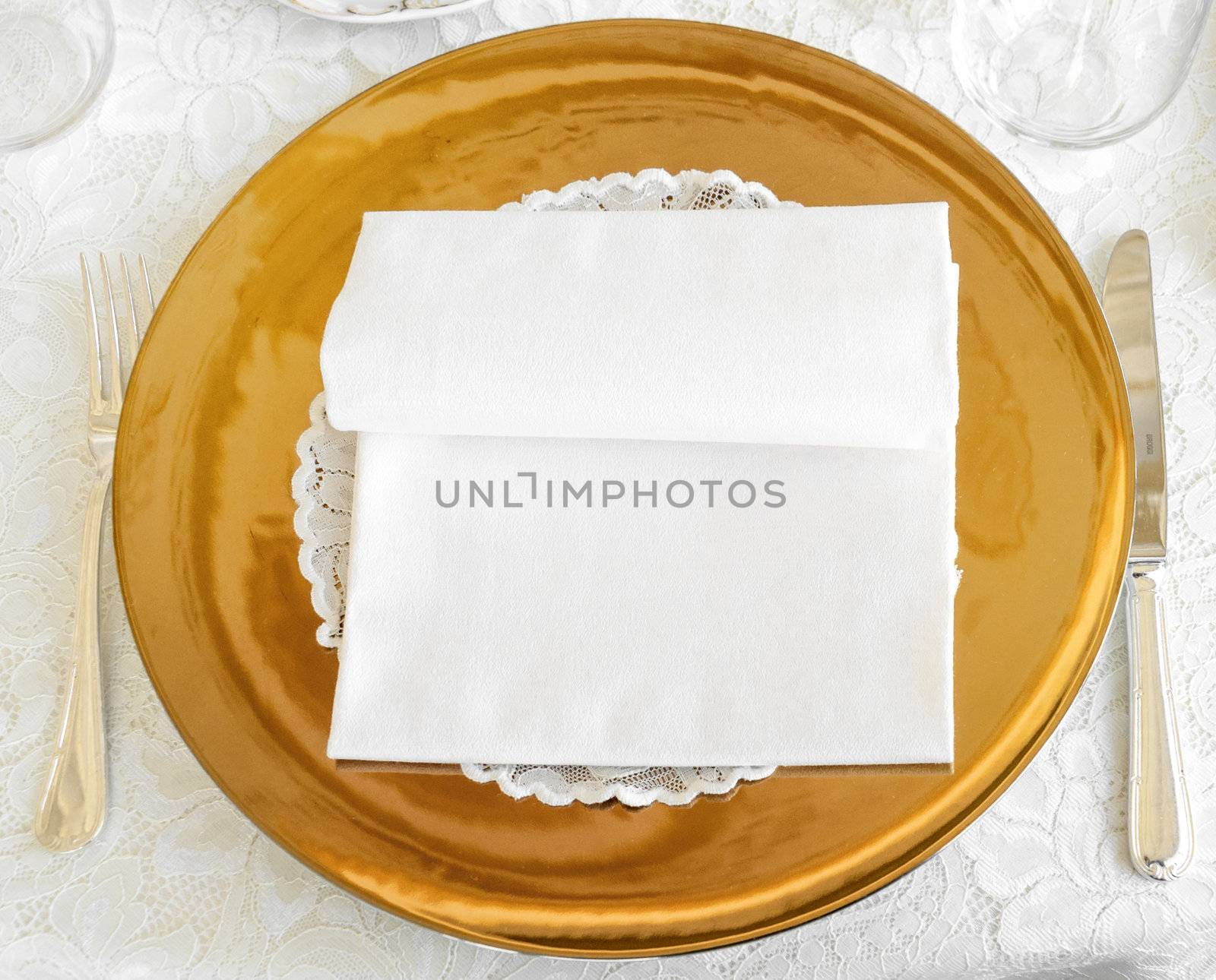 Golden plate in wedding catering with cuttlery and white napkin