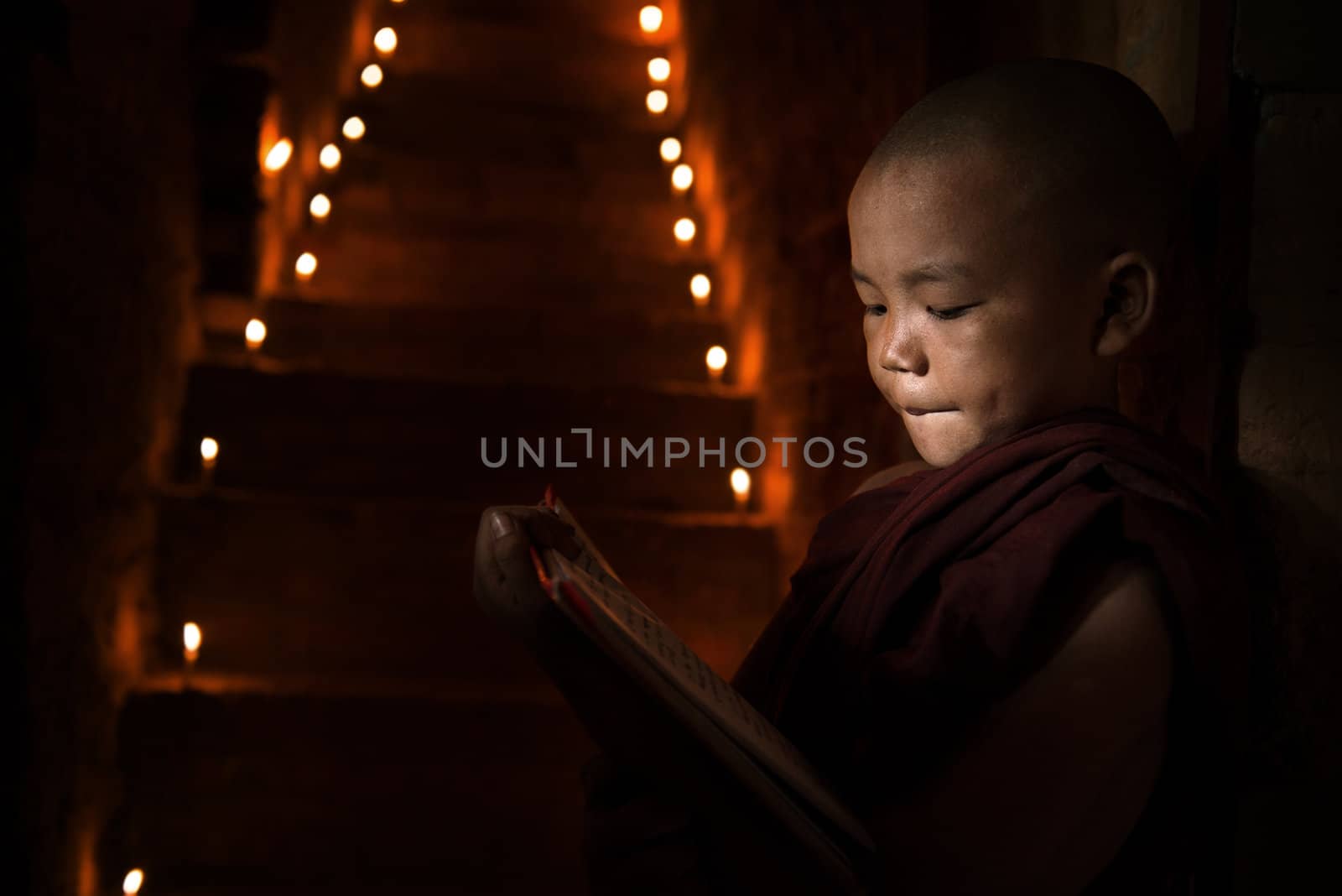 Little monk reading book inside monastery