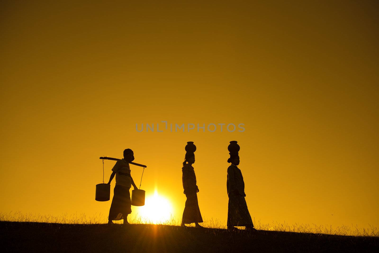 Silhouette of Asian traditional farmers carrying clay pots on head going back home, Bagan, Myanmar