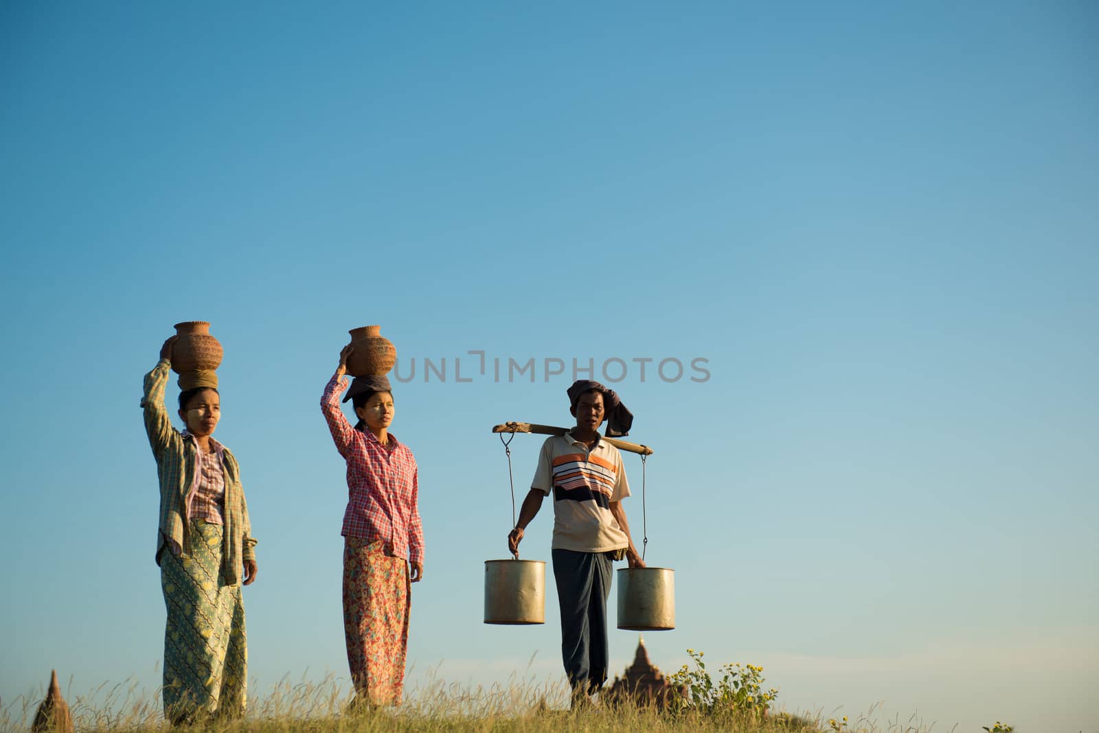 Group of Asian traditional farmers carrying clay pots on head going back home, Bagan, Myanmar