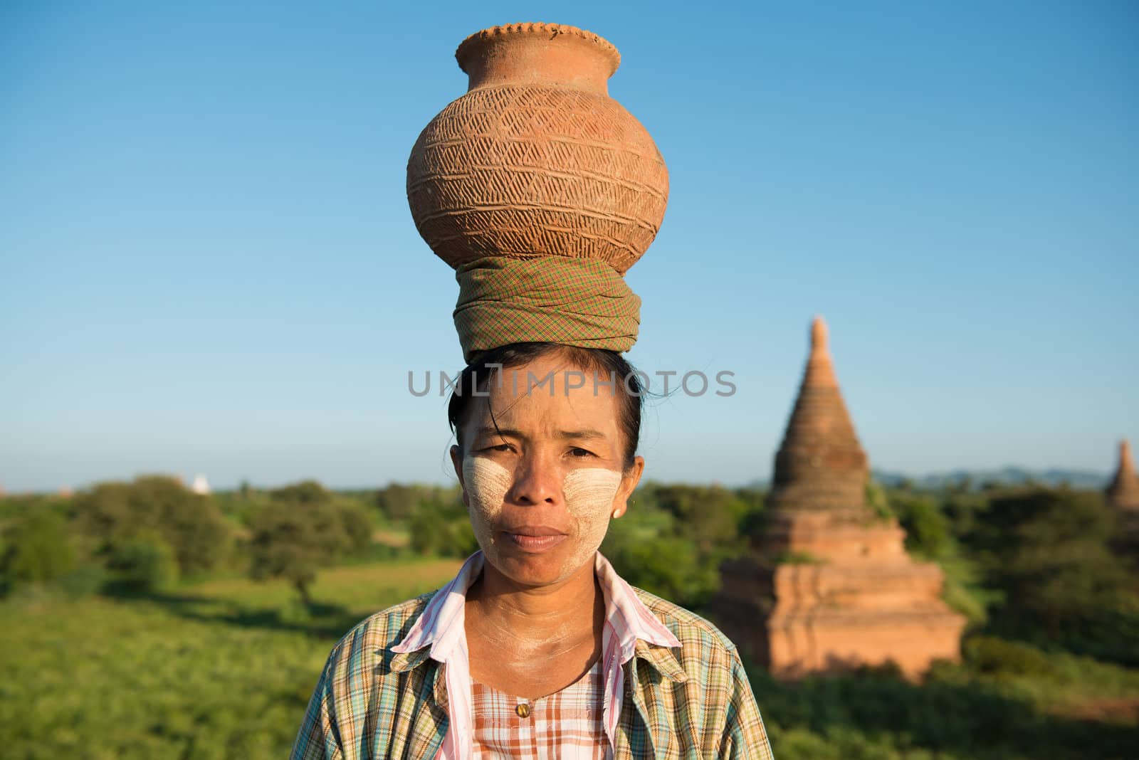 Portrait of Asian traditional farmer carrying clay pot on head going back home, Bagan, Myanmar 