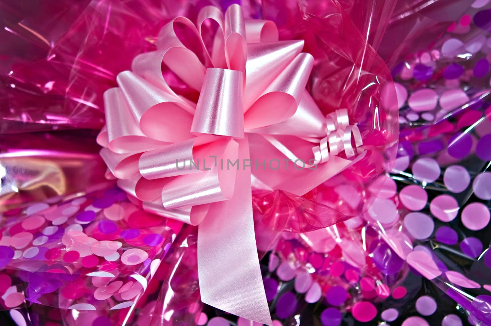 A pink bow on colorful wrapping paper.