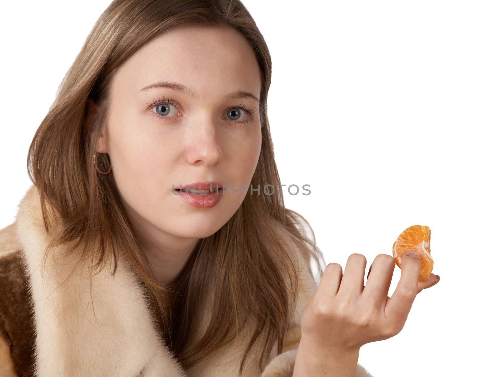 The girl in a fur coat holds segment of  tangerine on white background