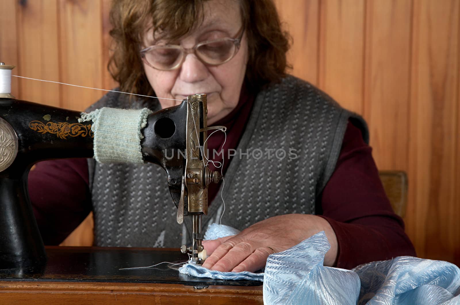 The old woman sews on the sewing machine
